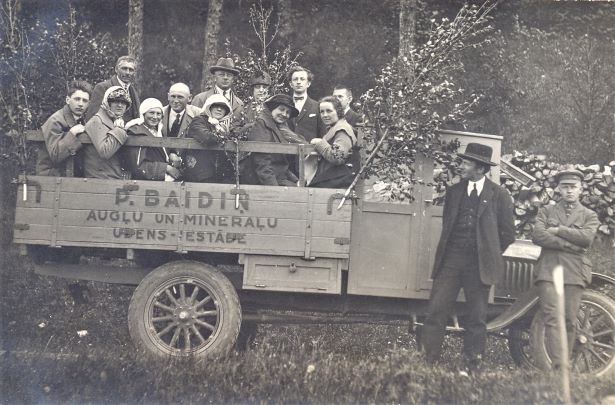 Cilvēku grupa vaļējā smagajā auto. 1930.gadi. Sēd 1.no kreisās komponists Jānis Norvilis. Foto autors nav zināms