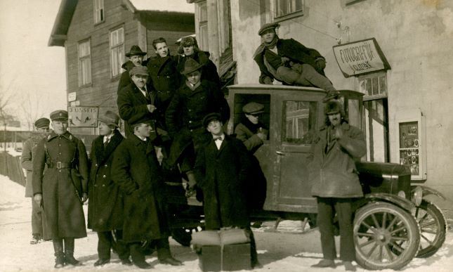 Smagā automašīna pie J.Glīznieka fotodarbnīcas Madonā. 1928.gada 2.janvāris. No labās 2.stāv Pēteris Stepāns (māte Kaileņu skolā strādāja par pavāri). No kreisās augšējā rindā 1.kurpnieks Kažmers (ar platmali). Jāņa Glīznieka foto